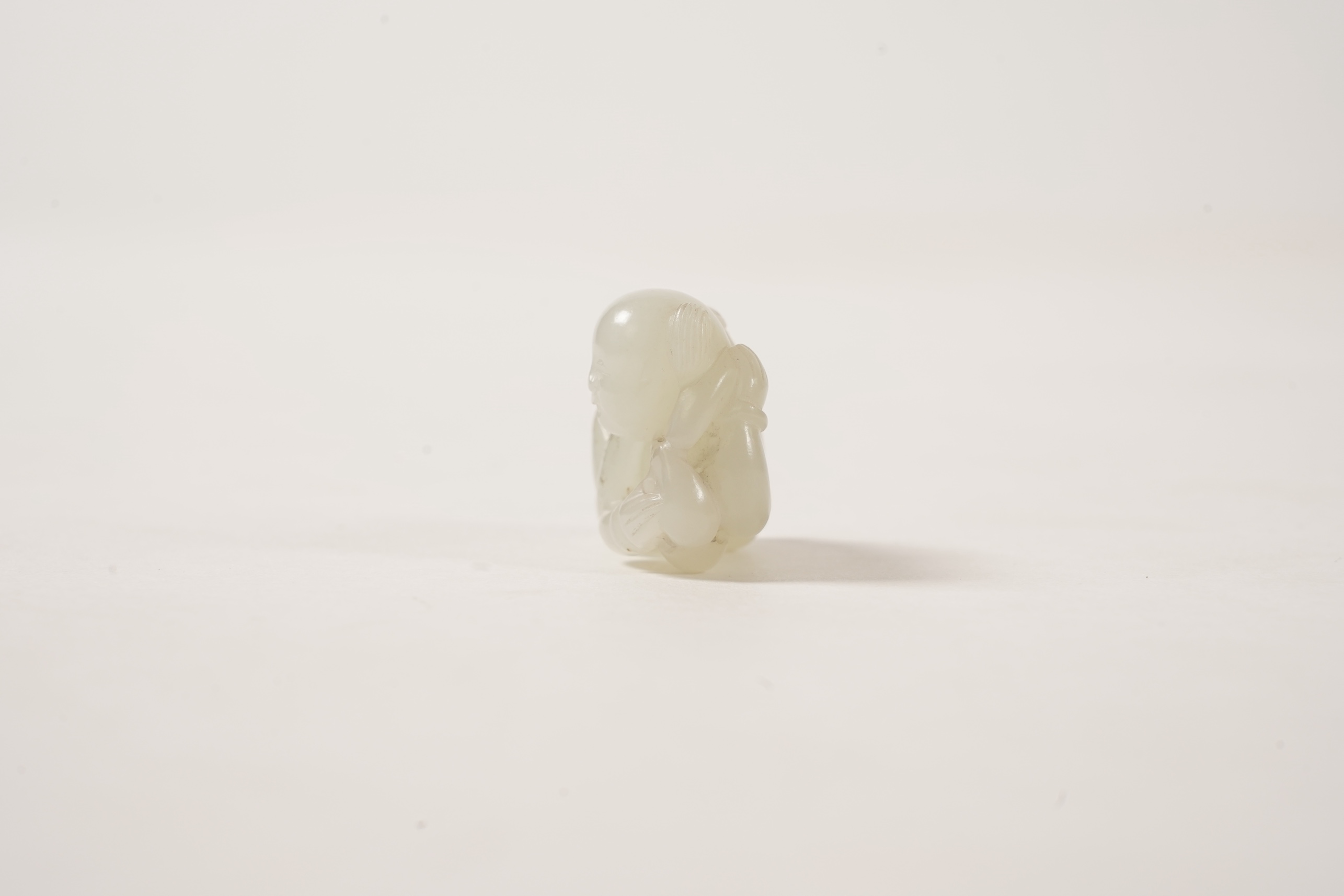 A Chinese white jade figure of a crouching boy, 19th/20th century